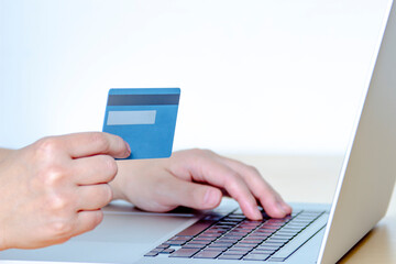 A Person online shopping with a credit card and a laptop.