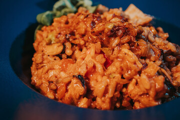 Closeup shot of pilaf with bacon and basil in a blue bowl