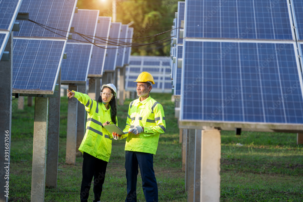 Poster Technician working with engineer planning new ecology project around field of solar panels.