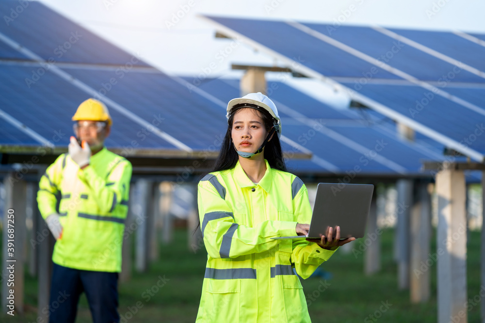 Poster Technician working with engineer planning new ecology project around field of solar panels.