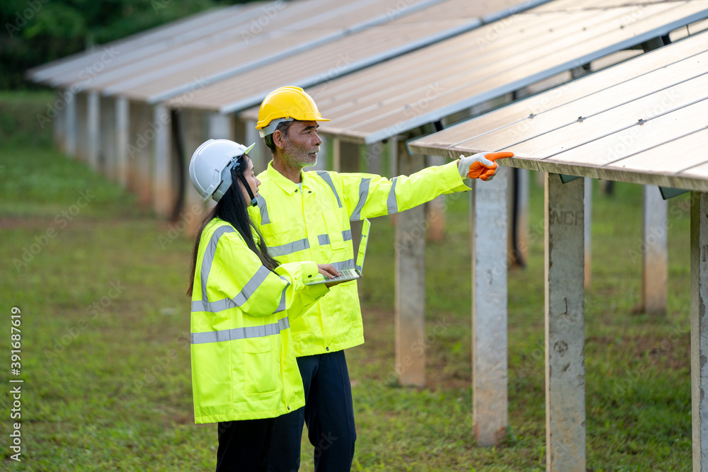 Poster Technicians and engineer in long sleeve shirts reflective vests and hard hats discussing something about solar panel power,Solar power plant to innovation of green energy for life.