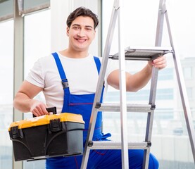 Young repairman climbing ladder at construction site