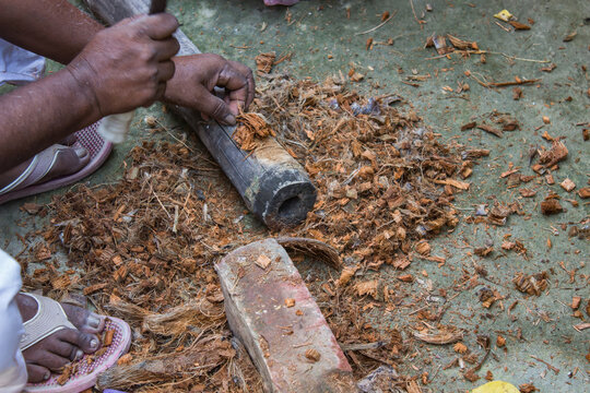 Local indian man chopping coconut husk and wood with katari for gardening and firewood. traditional indian way.