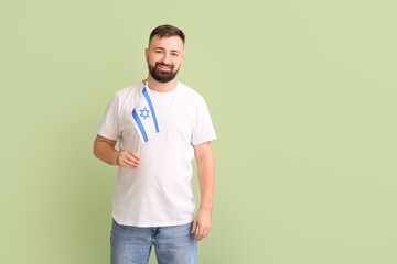 Fototapeta premium Man with the flag of Israel on color background