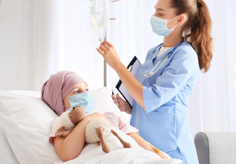Nurse and little girl undergoing chemotherapy course in clinic