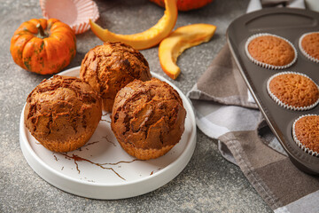 Plate with tasty pumpkin muffins on table