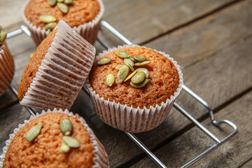 Cooling rack with tasty pumpkin muffins on table, closeup
