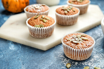 Tasty pumpkin muffins on color background