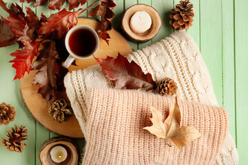 Autumn composition with stylish clothes and cup of tea on wooden background