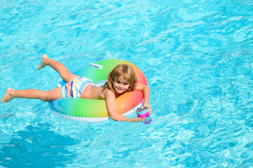 Cute funny little toddler boy in a colorful swimming suit and sunglasses relaxing with toy ring floating in a pool having fun during summer vacation in a tropical resort. Funny kids face.