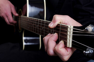 Obraz na płótnie Canvas The guitarist plays a black acoustic guitar.