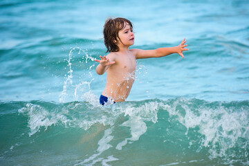 Kid boy playing and swimming in blue sea on summer. Blue ocean with wawes. Child boy swimming in sea.