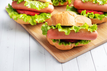 a few hot dogs on a wooden Board. Hot dog with lettuce tomato and sausage. Copy space.
