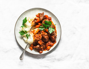 Burgundy beef stew with mashed potatoes on a light background, top view. Delicious comfort homemade food
