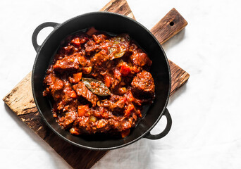 Burgundy beef stew in a cooking pan on a light background, top view. Delicious comfort homemade food