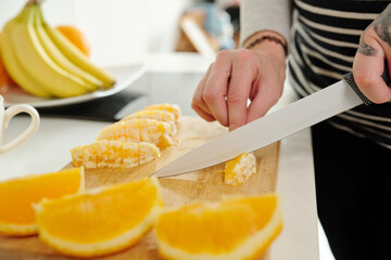 Close-up image of woman cutting oranges when cooking dinner at home