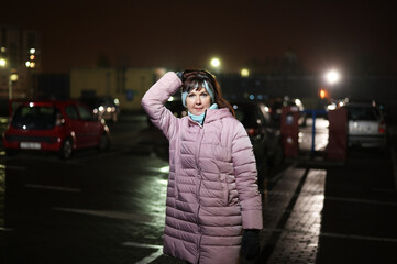 Photo of a woman in the city lights at night. The model stands directly in front of the camera against the background of city traffic.