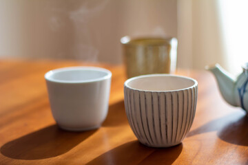 日の当たるテーブルに置かれた急須と入れたてのほうじ茶の入った湯飲み