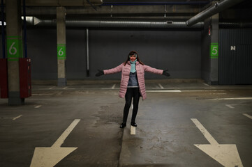 A model stands directly in front of the camera against the backdrop of an underground parking lot. Photo of a Caucasian woman in the city.
