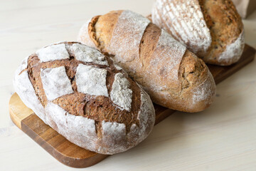 Fresh loaves of bread with wheat and grain on a white wooden table