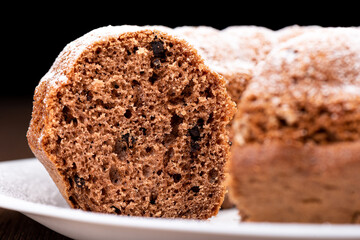 Macro shot texture of homemade cupcake slice with chocolate chips. Cupcake sprinkled with powdered sugar. Food background concept.