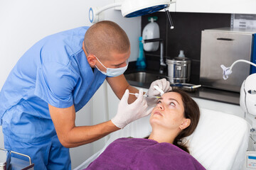 Young woman patient of beautician receiving hyaluronic acid injections