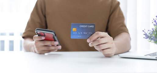 Young man with a credit card shopping online on a laptop.