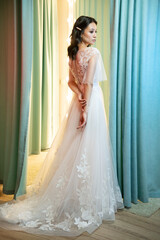 Fototapeta premium Portrait of a young bride in a fashionable wedding dress with beautiful makeup and hairstyle