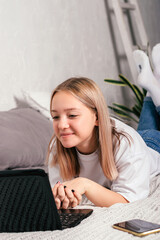 Video communication.Teenage girl lying on the bed and communicating via video chat,zoom using laptop.