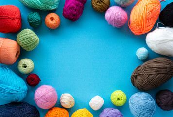 Knitting flat lay. Various colored balls of yarn on a blue background. Space for text
