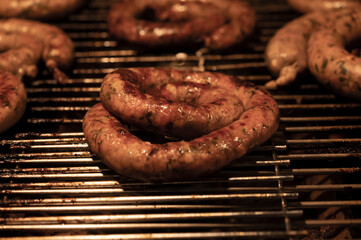 Coil of juicy beef sausage grilling over a BBQ