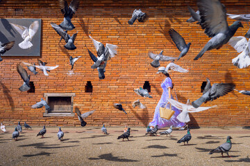 Asian woman tourist walks through the middle of a pigeon next to Tha Phae Gate in Chiang Mai,...
