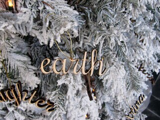 Word Earth wooden cutout decoration on white Christmas tree
