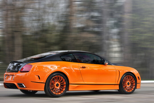 Kiev, Ukraine - April 20, 2015: Bentley Continental GT Mansory against the background of trees. Luxurious tuned car. Orange Bentley car