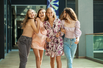 Four happy girlfriends walking in shop