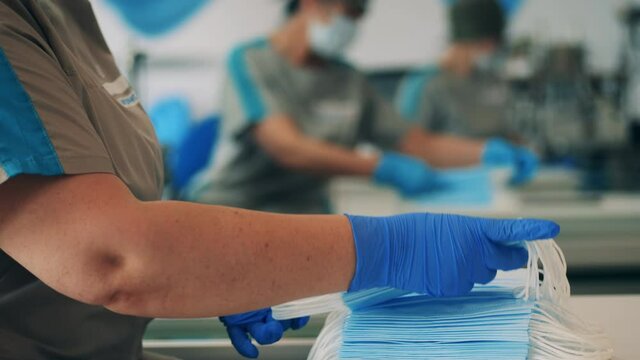 Female factory worker stacking face masks together