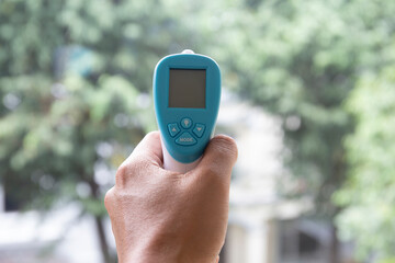 close up of a hand holding a digital infrared thermometer (thermometer gun) 