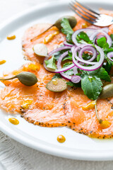 Salmon carpaccio and arugula salad with onions and capers
