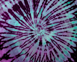 Spiral tie dye texture. Hippie tie-dye wallpaper. Boho festival tiedye background in purple green.