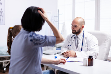 Fototapeta premium Mother and daughter at doctor appointment in hospital office. Healthcare physician specialist in medicine providing health care services treatment examination.