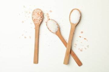 Wooden spoons with salt on white background, top view