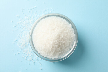 Glass bowl of salt on blue background