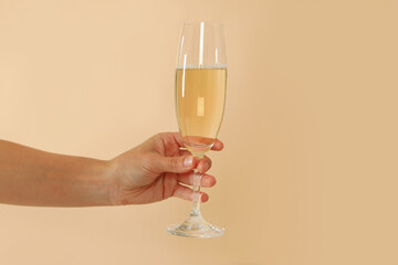 Female hand hold champagne glass on beige background