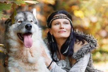 Portrait of a young charming woman with an Alaskan Malamute dog in the autumn forest
