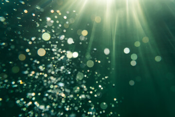 Underwater picture in the baltic sea with sun rays in the background and beautiful bubbles as bokeh balls in the forground