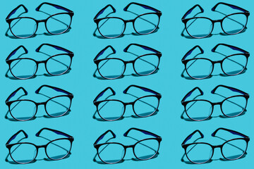 Glasses for vision pattern. Copy glasses on a light blue background. Glasses with transparent lenses lying in a row. Horizontal.