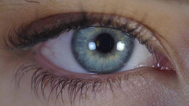 Caucasian young woman's blue eye opening, close up