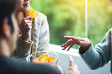 Closeup image of friends eating and sharing potato chips together