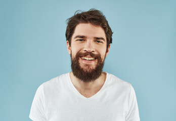 Fototapeta premium Handsome man with a beard on a blue background white t-shirt portrait