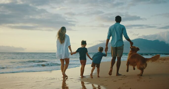 Happy young family playing with cute golden retriever dog on the beach